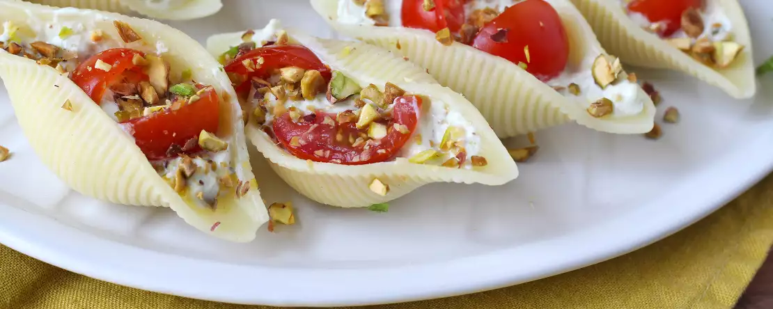 Chilled stuffed conchiglioni with stracciatella, pistachios, cherry tomatoes, and lemon