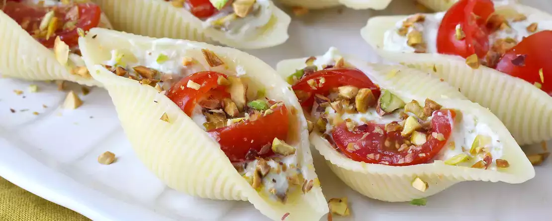 Chilled stuffed conchiglioni with stracciatella, pistachios, cherry tomatoes, and lemon