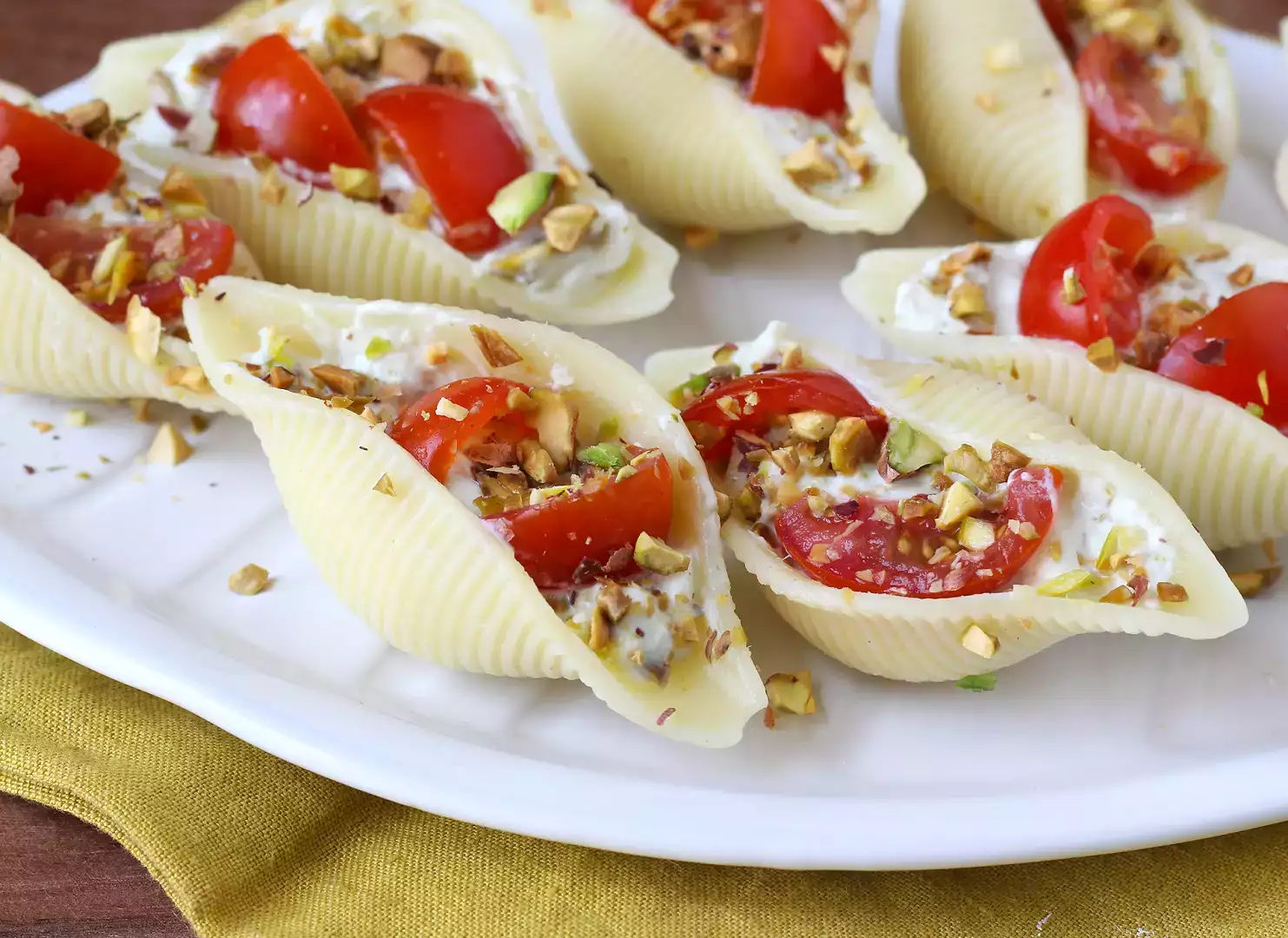 Chilled stuffed conchiglioni with stracciatella, pistachios, cherry tomatoes, and lemon