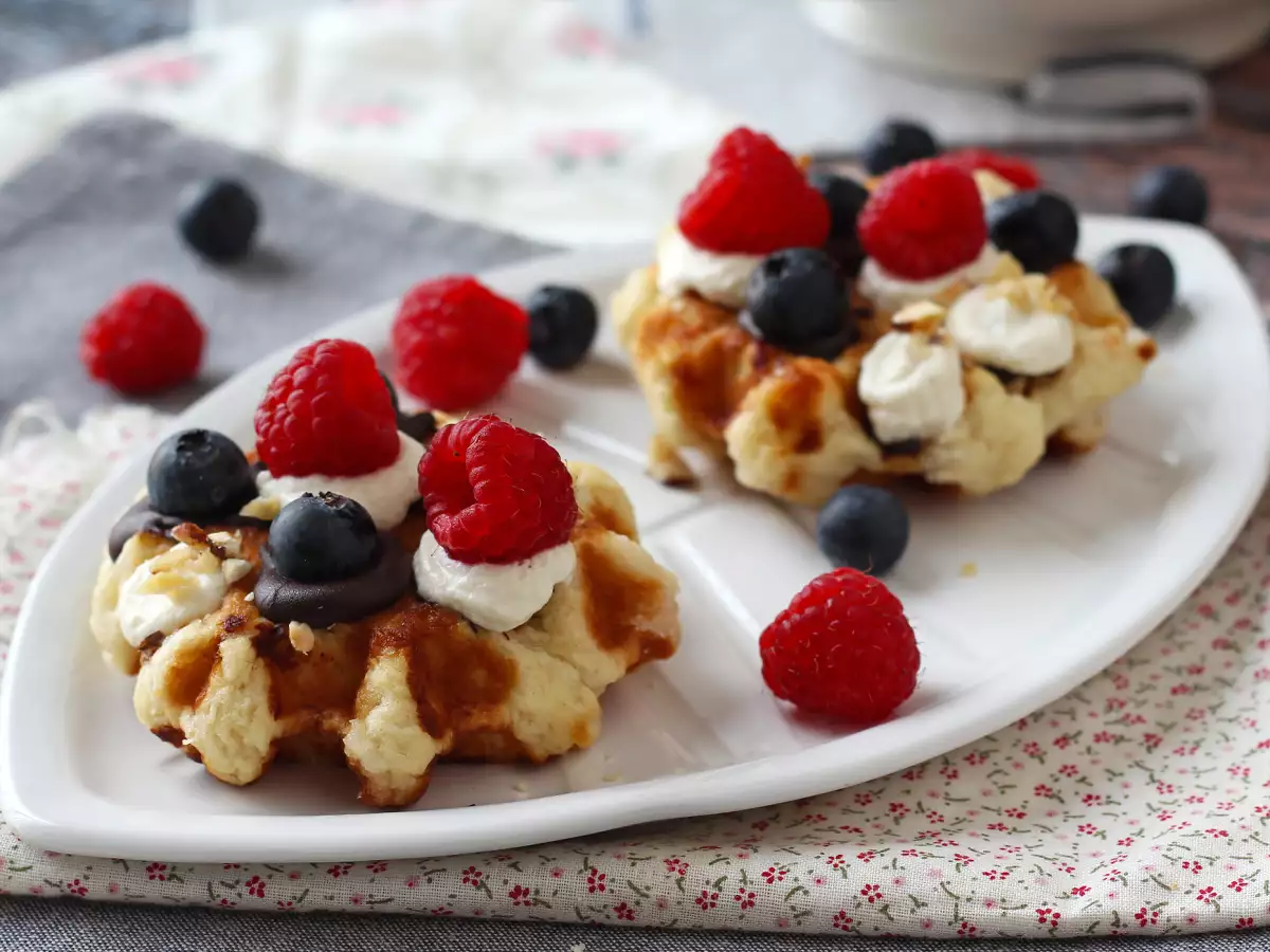 Waffles topped with fruit, chocolate and whipped cream